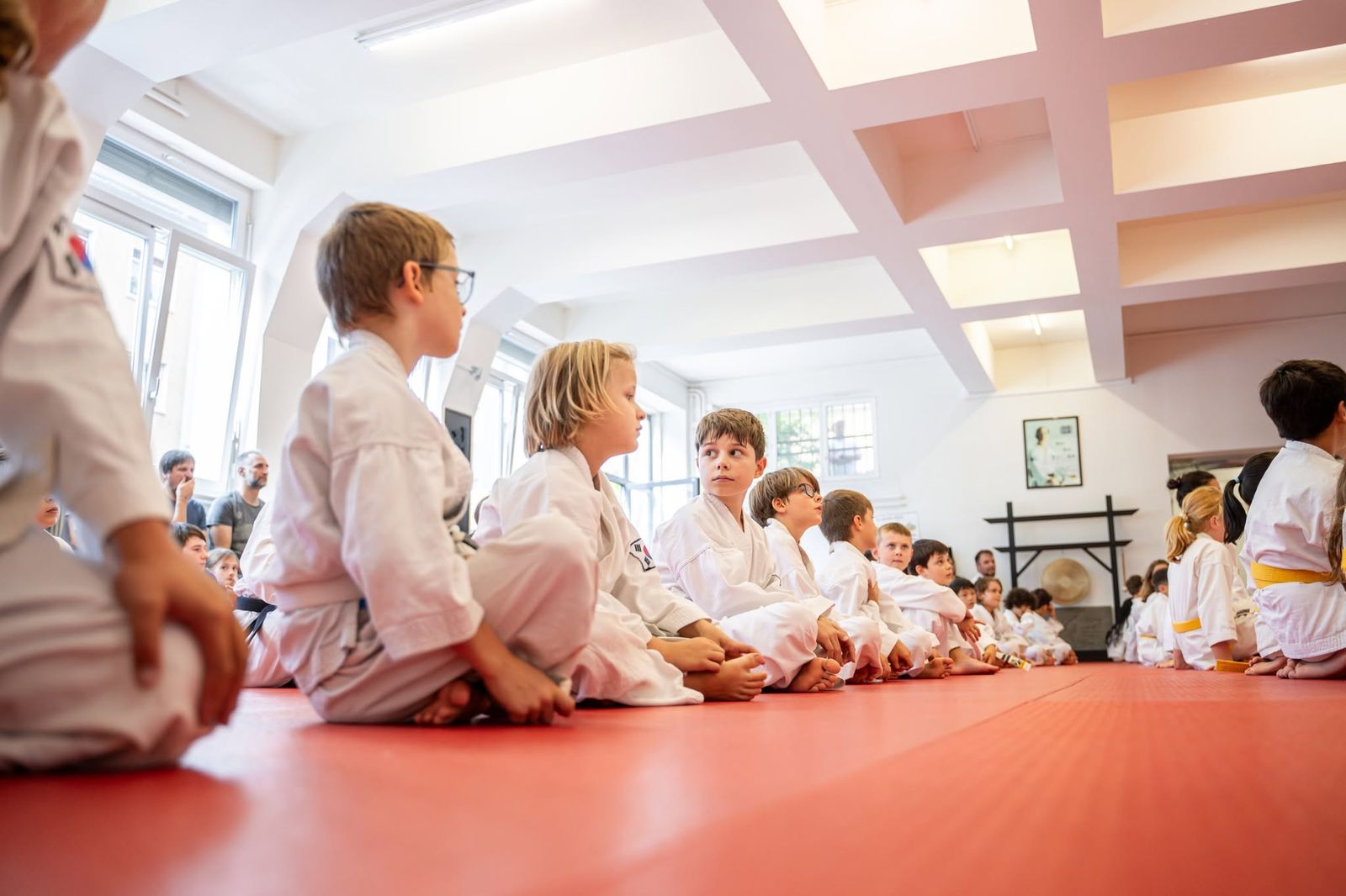 Kinder sitzen in der Reihe und hören zu, Eltern schauen zu — Kindertraining in Winterthur